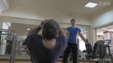 斯坦尼康拍摄的两<strong>个人</strong>在健身房的<strong>工作</strong>，一<strong>个人</strong>做坐在腹部长凳上，而另一个
